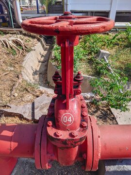 ​Red industrial gate valve with handwheel mechanism outdoors