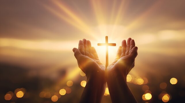 Hands holding a cross against radiant light.