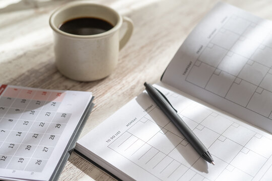Desk setup showing an open planner, calendar, pen, and a cup of coffee, representing planning, productivity, and effective time management for daily goals and professional life