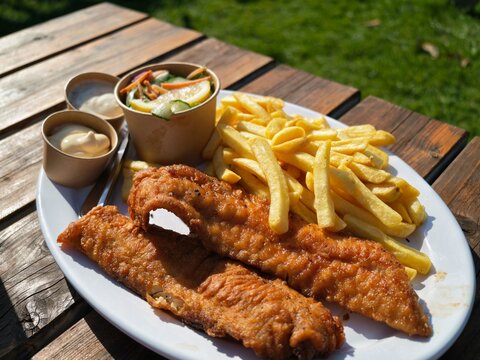 Traditional british fish and chips served on a white plate with french fries