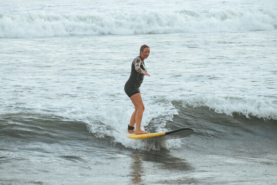 Young female surfer catching a wave on a yellow surfboard in the ocean