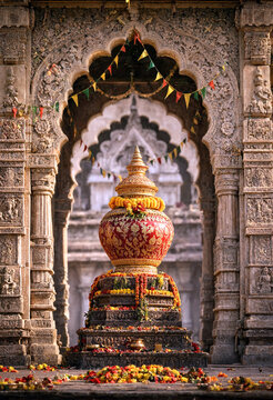 Ornate golden kalash pot decorated with flowers and garlands in a traditional Indian temple archway