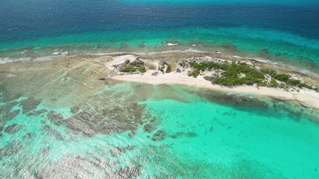 Drone captures aerial view of Petit Tabac tropical island surrounded by turquoise Caribbean water, coral reef and white sandy beach known from Pirates of Caribbean film
