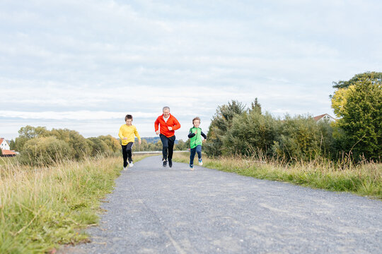 Father and sons jogging with white dog outdoor