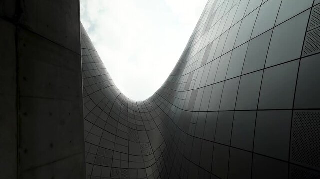 Dark concrete and glossy tiled walls rise into a narrow opening of sky, creating a dramatic urban canyon composition.