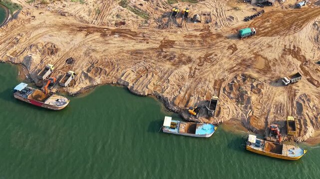 Sand mining activity along river shore with boats and excavator extracting sand India riverbank industry