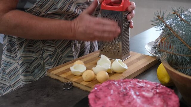 Preparing a traditional family salad. Grating eggs.