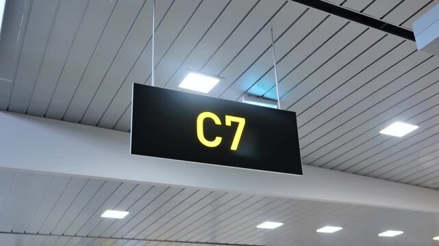 Yellow C7 gate sign guides passengers through modern Riga airport terminal