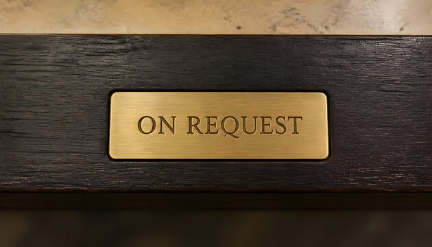 Golden brass On Request plaque embedded in dark wooden surface