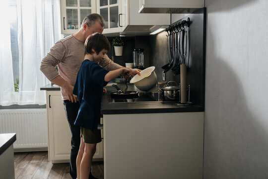 Father and son cooking breakfast together in kitchen