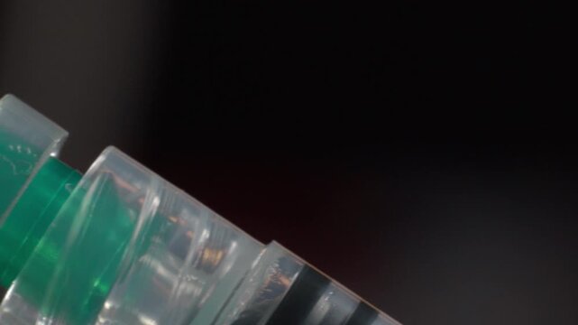 Transparent medical syringe shown in macro closeup without a needle. Clear plastic components and measurement markings create a detailed medical object against a dark background.