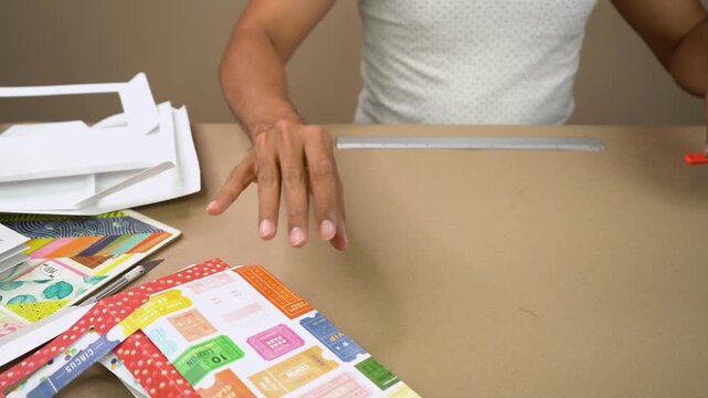 Hands assembling and folding cardstock frames with craft tools on tabletop