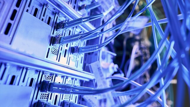 High speed blue fiber optic cables connected to server rack equipment with technology datacenter computer hardware