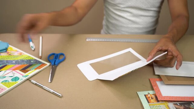 Hands assembling and decorating paper crafts with tools on tabletop workspace