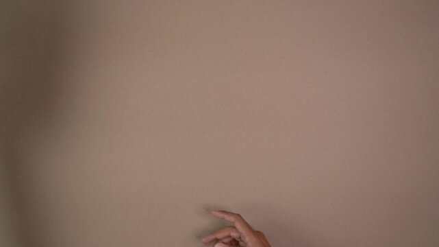 Hands gather and remove sheets of white textured cardstock from flat surface