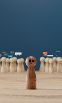 Sad wooden figure standing alone with speech bubbles behind, cyberbullying concept, social media harassment, feeling excluded and gossiped about.