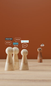 Wooden figure with question mark feeling isolated while group talks behind, cyberbullying concept, social exclusion, workplace gossip and rumor.