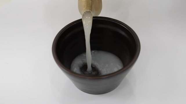 Close-up Fixed Shot of Pouring Traditional Korean Rice Wine Makgeolli into a Bowl (Korean Culture, Beverage)