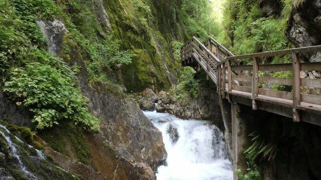 Waterfall flowing through the moss-covered Wimbachklamm gorge with a wooden walkway, Bavaria