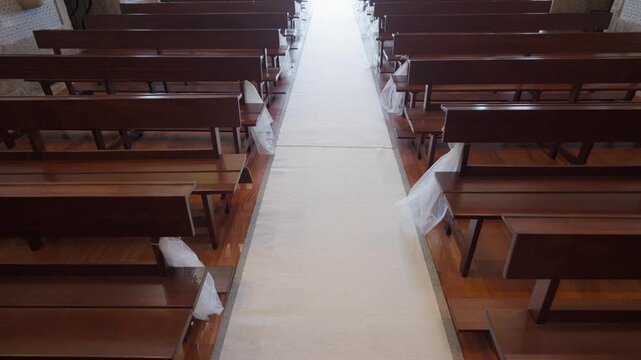 White aisle runner leading between wooden pews decorated with tulle in Portuguese church