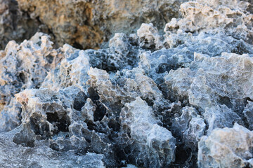 Fototapeta premium Rough, weathered grey limestone rock formation featuring sharp, pitted ridges and porous natural crevices.