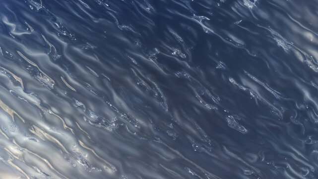 Close view of rippling calm body of water with its surface shimmering under light to create a pattern of silver highlights with a deep blue background
