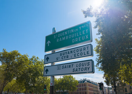 Road signs pointing towards French cities under a bright blue sky
