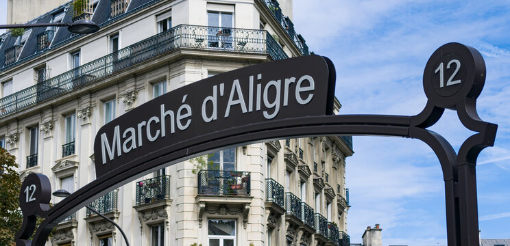 Marche d'Aligre Market sign against classic Haussmann building, depicting Parisian daily life