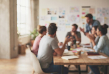 Fototapeta premium Blurred business team collaborates around a table in a bright modern office with sticky notes on the wall.