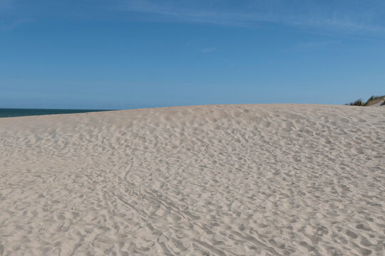 Sandy dunes on the North Sea coast at Oostduinkerke Belgium beneath a clear blue summer sky with a distant sea horizon view