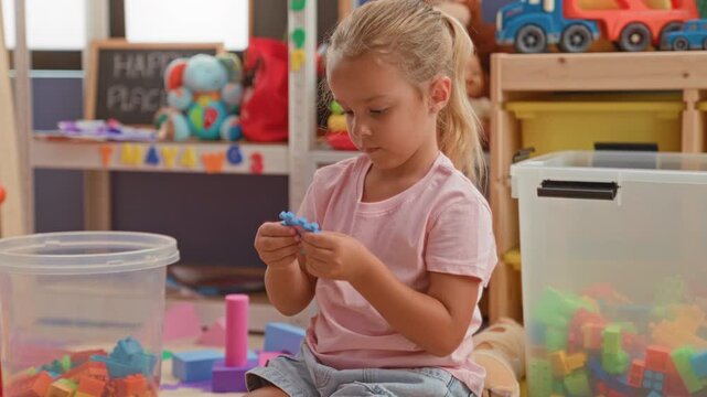 Little girl assembling foam puzzle pieces and stacking colorful blocks with hands on a playmat inside a building; calm concentration.