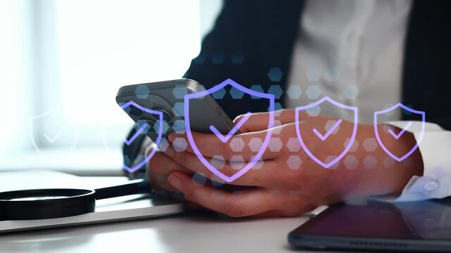 A person sits at a desk with a smartphone in hand. The setting includes a tablet and a circular object. Security icons appear in the background, suggesting a focus on digital safety.