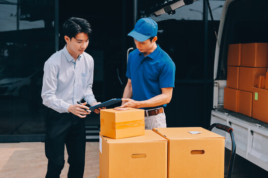 Young businessman signing a delivery receipt document on a clipboard held by a courier in a blue uniform.