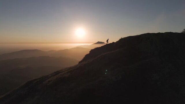 Man hiking and running on the top of the mountains at sunset time, at the Basque Country.