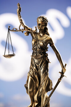 Justitia figurine in front of paragraphes, close-up