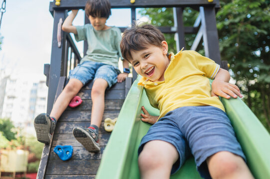 A happy boy smiles while sliding down a playground slide outdoors