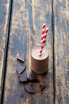 Glass bottle of cocoa and bittersweet chocolate on wood