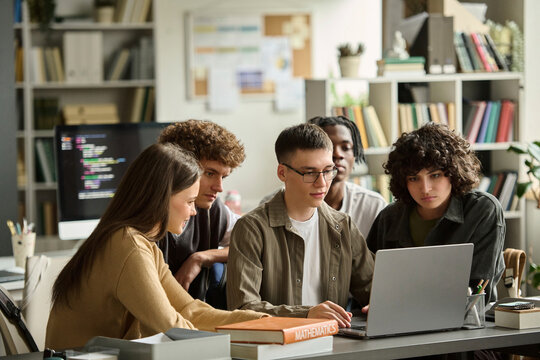 Diverse students use a laptop together in the library