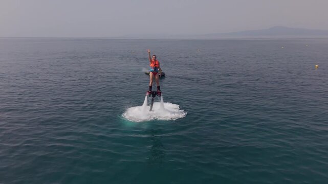 Woman Greeting the Camera While Hovering on a Flyboard Above the Sea off Kalamata, Greece, Drone View