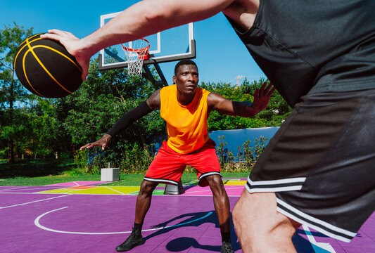 Male athletes play a competitive basketball game on an outdoor court