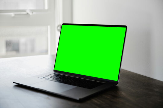 Laptop with Green Screen Chroma Key Display on Wooden Desk by Window