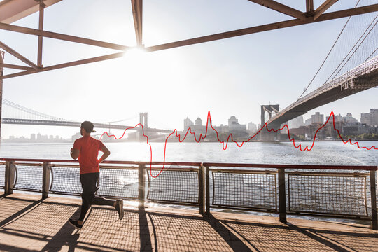 USA, New York City, man running at East River with line graph behind him