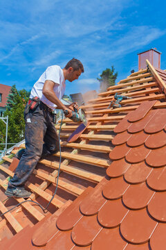 Germany, Baden-Wuerttemberg, Stuttgart, Mid adult man cutting roof tile