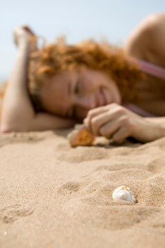 Young woman on beach, holding shell