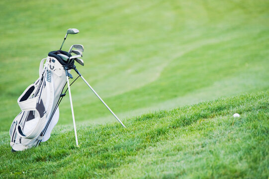 A golf bag stands on the green grass at a golf course in Italy