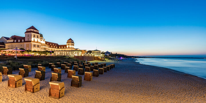 Germany, Mecklenburg-Vorpommern, Binz, Hooded beach chairs standing along beach in front of Kurhaus Binz at dusk