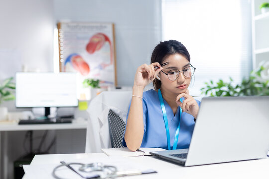 Female healthcare professional reviewing medical information on laptop in modern clinic, representing healthcare research, digital records, telemedicine, clinical analysis, patient care.