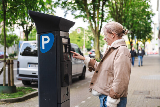 Woman Paying at Curbside Parking Meter on City Street