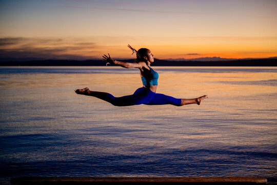Hispanic woman performing acrobatic split jump exercise
