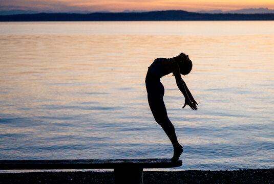 Hispanic woman performing yoga acrobatics backbend outdoors